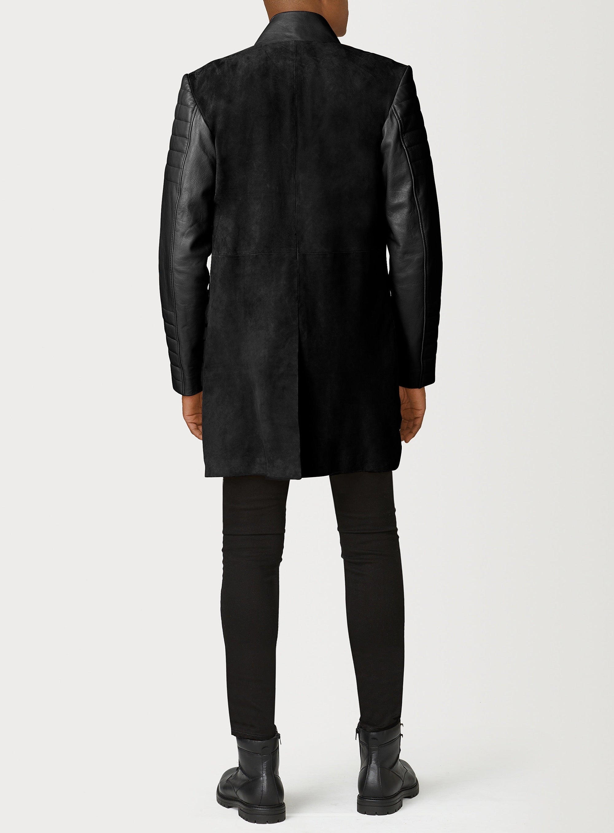 A Beautiful Black Suede Trench Coat, created by designer brand PRSVR. The PRSVR Lab Coat has a suede Body, and lambskin leather sleeves that show off a padded ribbed design on the shoulder and wrist of the sleeve. 