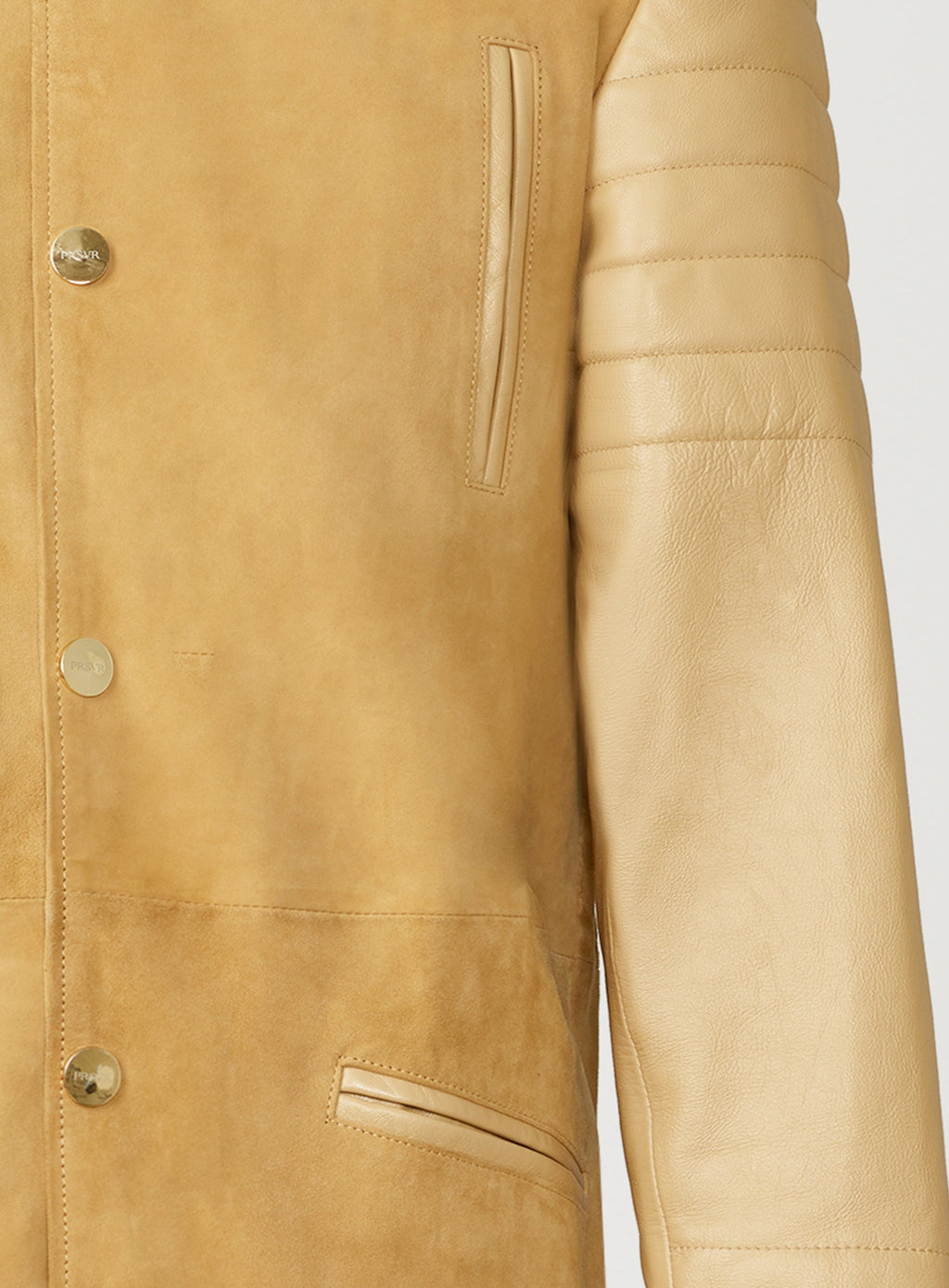 A Beautiful Suede Trench Coat, created by designer brand PRSVR. The PRSVR Lab Coat has a suede Body, and lambskin leather sleeves that show off a padded ribbed design on the shoulder and wrist of the sleeve. 