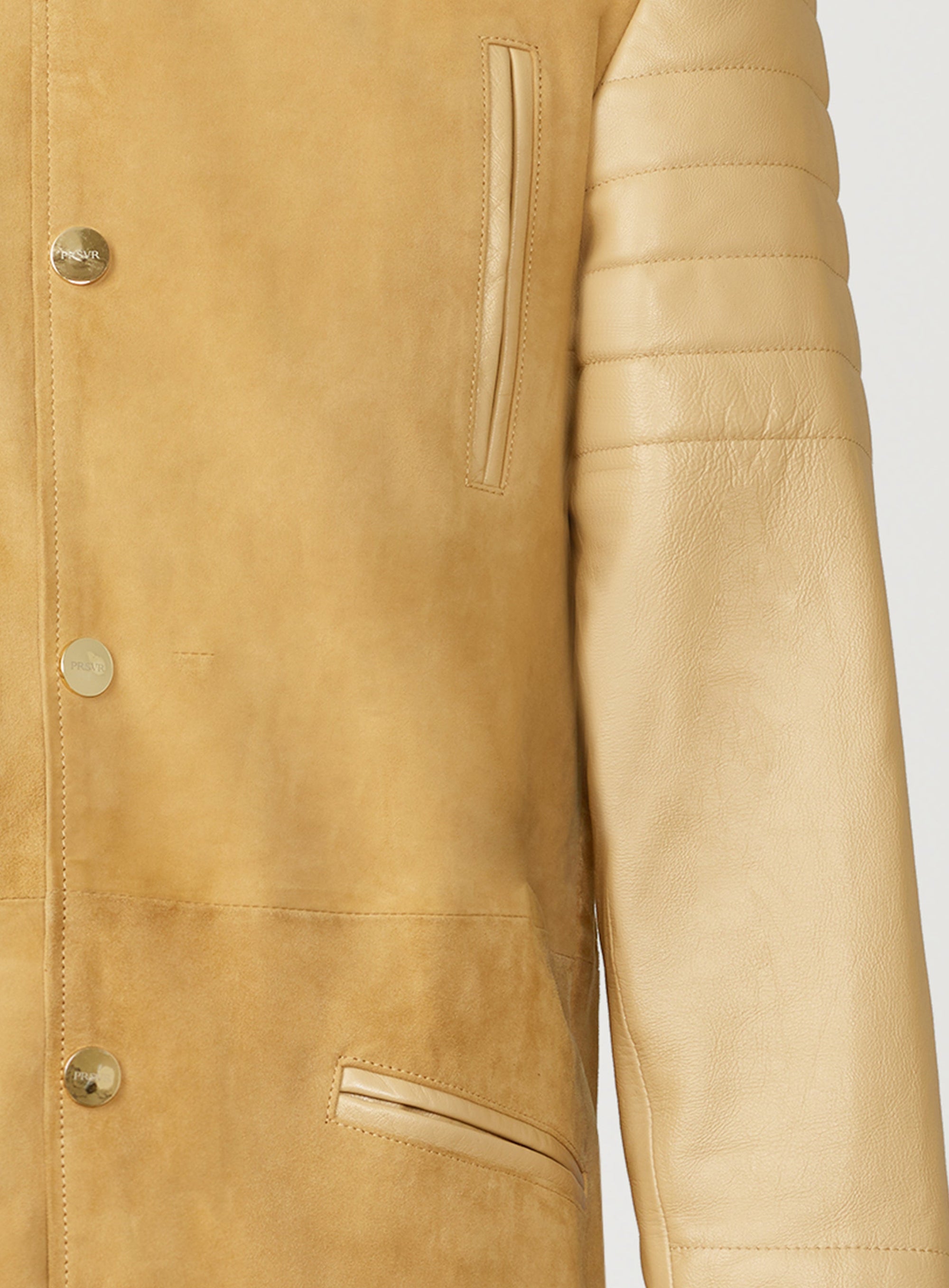 A Beautiful Suede Trench Coat, created by designer brand PRSVR. The PRSVR Lab Coat has a suede Body, and lambskin leather sleeves that show off a padded ribbed design on the shoulder and wrist of the sleeve. 